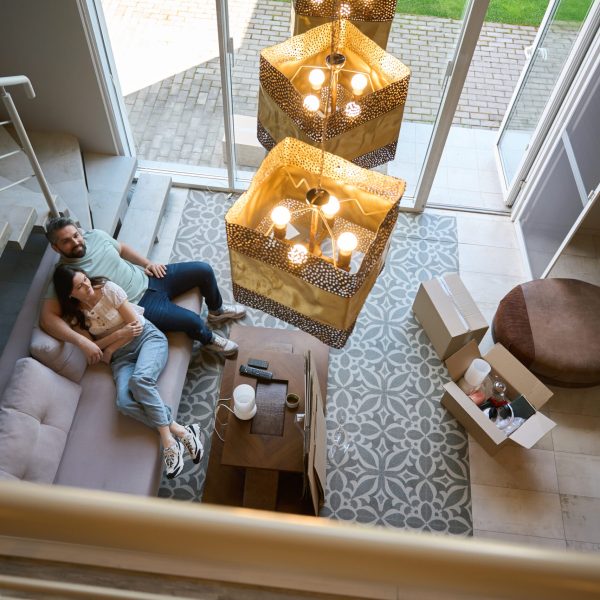 Top view of woman lying on bed and man who sitting near to her and looking at camera indoors