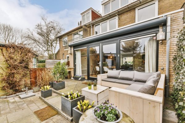 Neat paved patio with sitting area and small garden near wooden fence