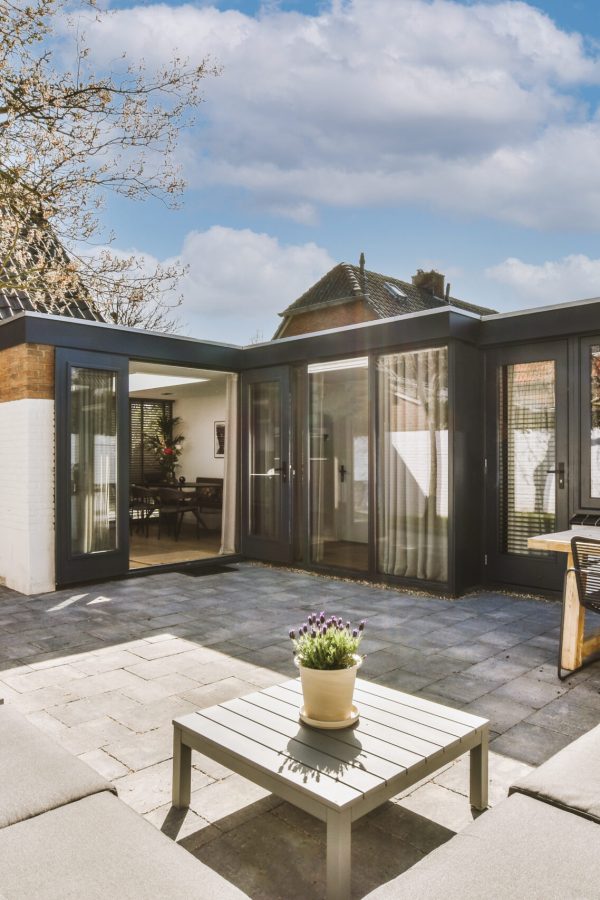 Neat paved patio with sitting area and small garden near wooden fence